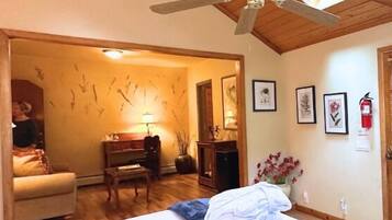 A bedroom with a bed, a desk, a chair, and a ceiling fan.