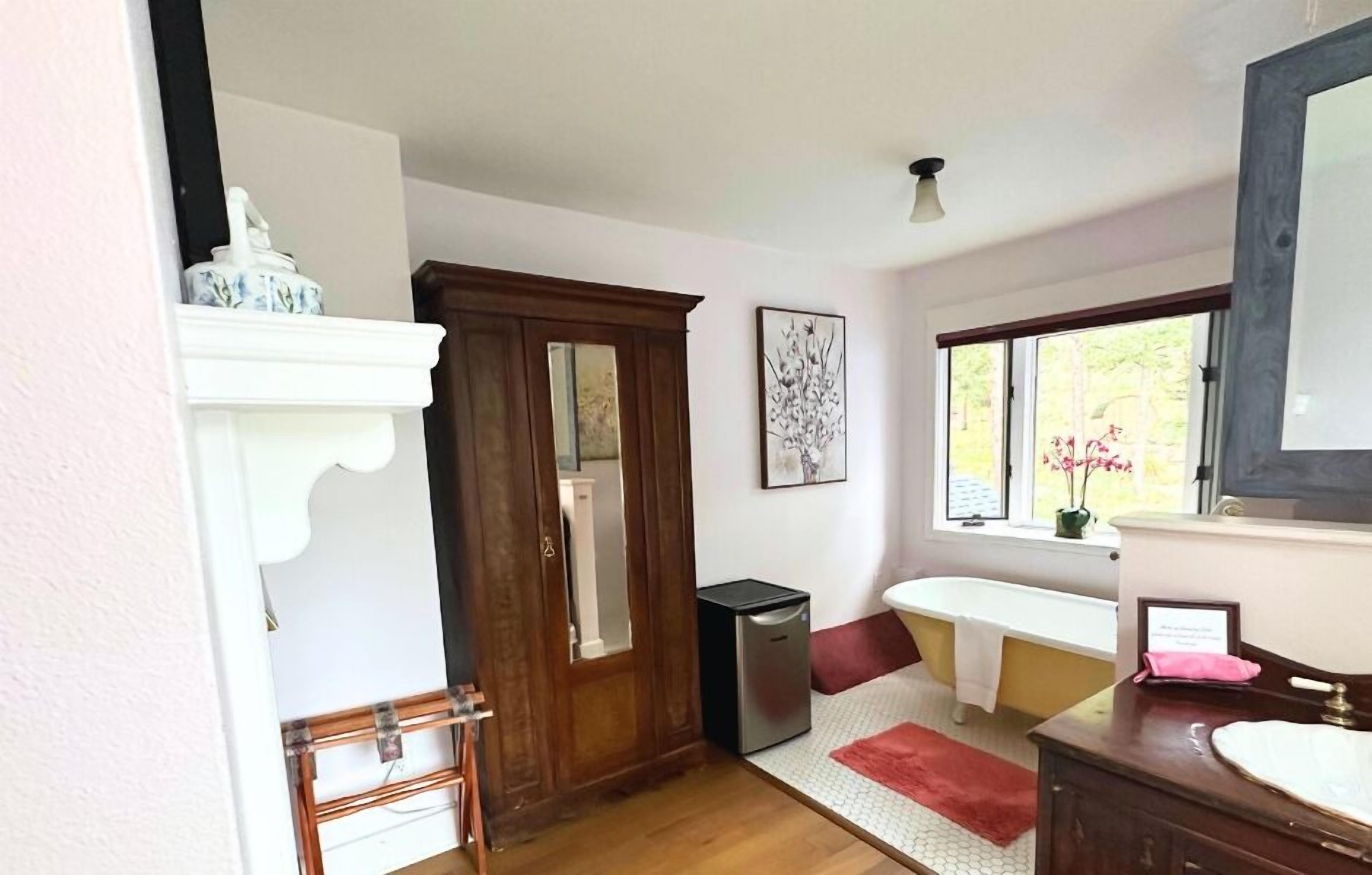 Un baño con puerta de madera, un lavabo, un espejo y una ventana con vistas a árboles.