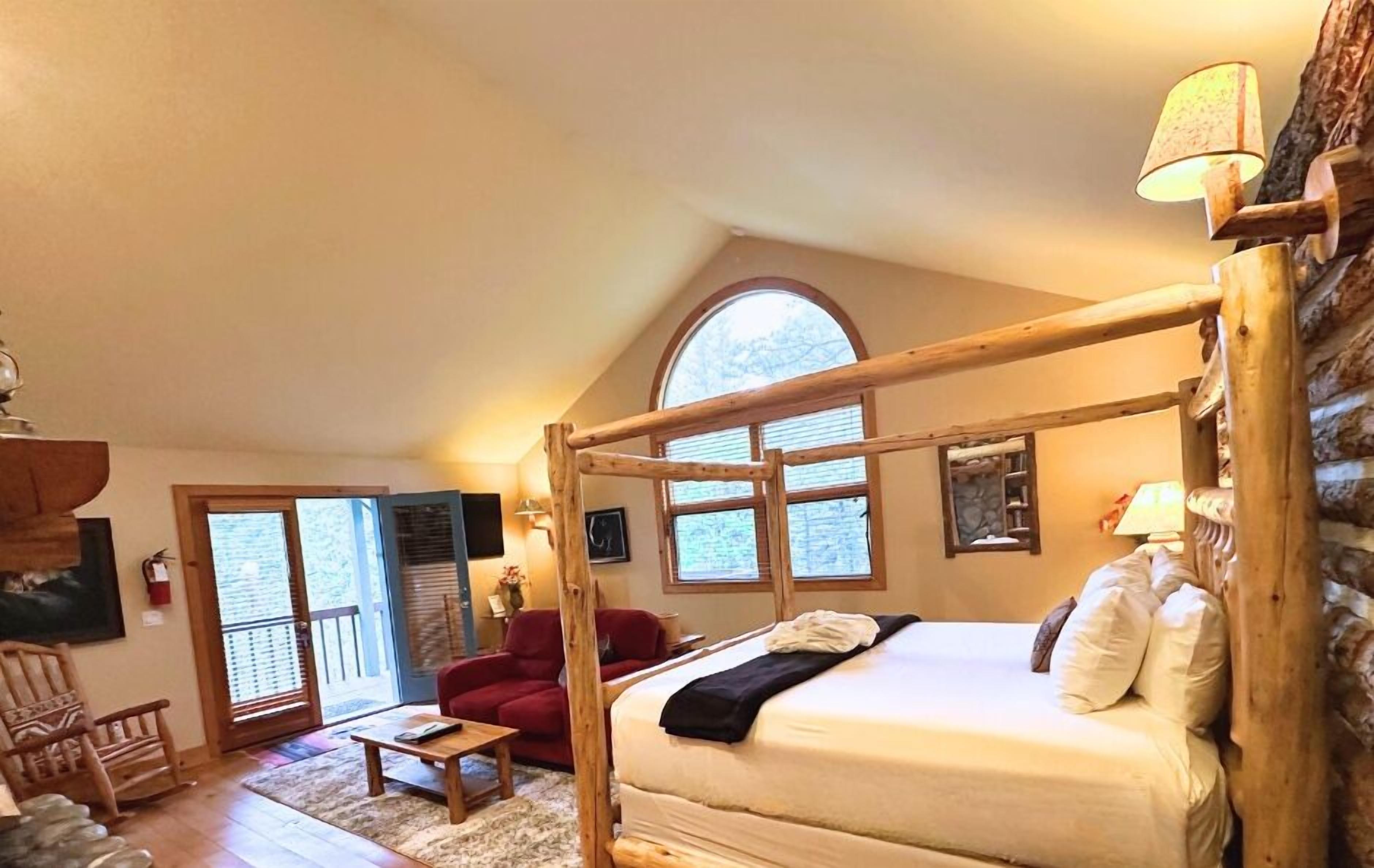A cozy bedroom with a wooden four-poster bed, a red armchair, and a small table.