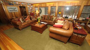 A cozy living room with a brown leather sofa set, a coffee table, and a bookshelf filled with books.