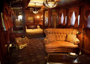 Una habitación de estilo antiguo con una cama, un chaise-lounge, un aparador y una araña.