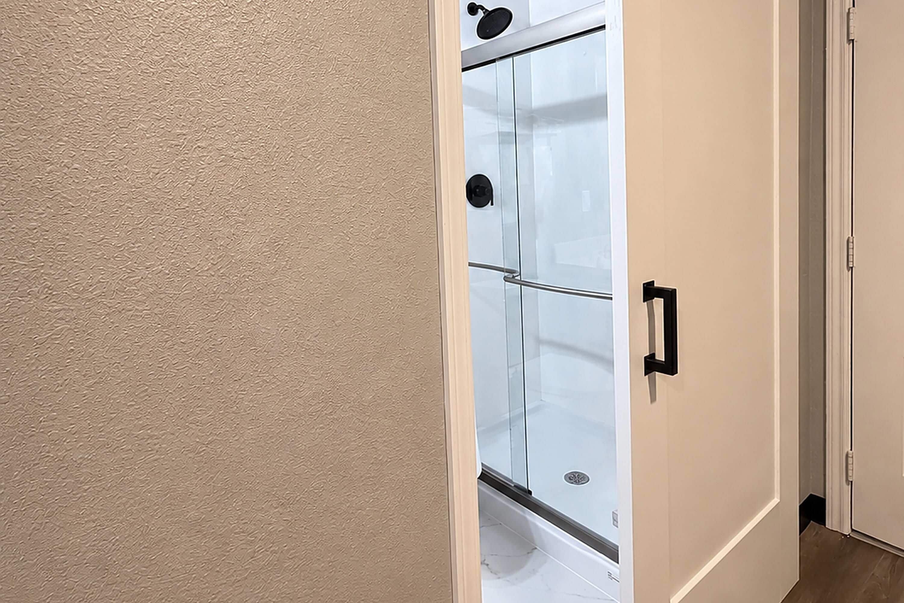 Una puerta que da a un baño con ducha, inodoro y lavabo.