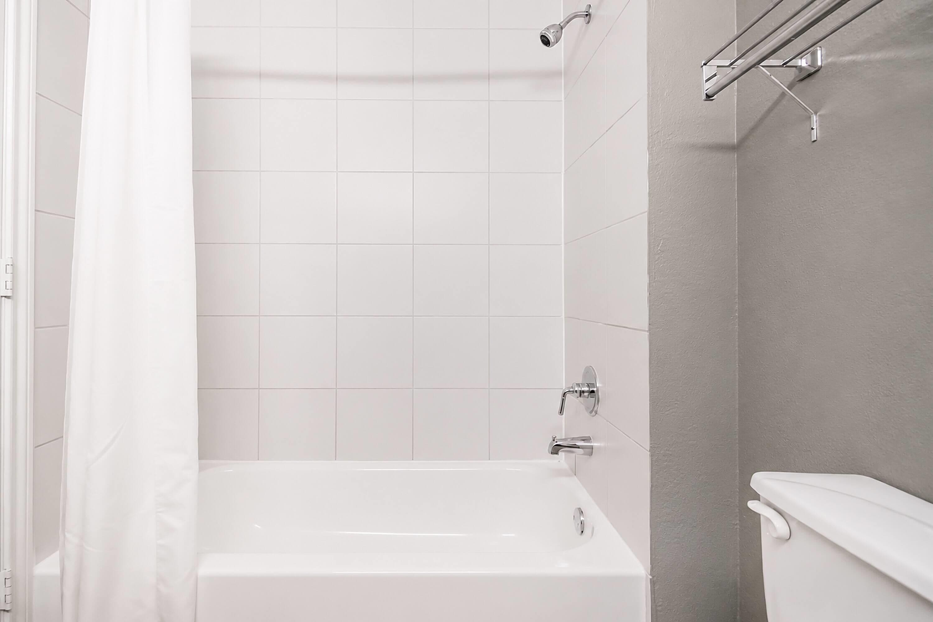 A modern bathroom with a bathtub, a shower, and a toilet.