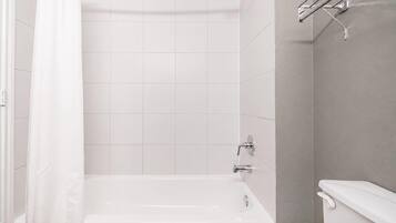 A modern bathroom with a bathtub, a shower, and a toilet.