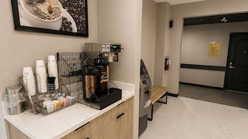 A coffee station with a coffee machine, cups, and a coffee pot.