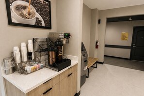 A coffee station with a coffee machine, cups, and a coffee pot. - Super 8 by Wyndham Brenham TX (Brenham)