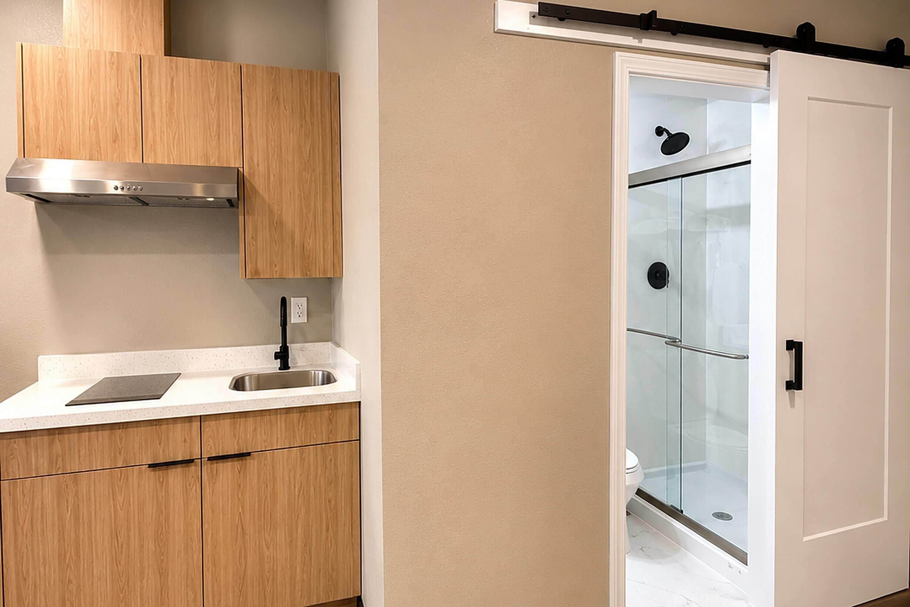 A modern kitchen with wooden cabinets, a stainless steel range hood, and a white countertop.