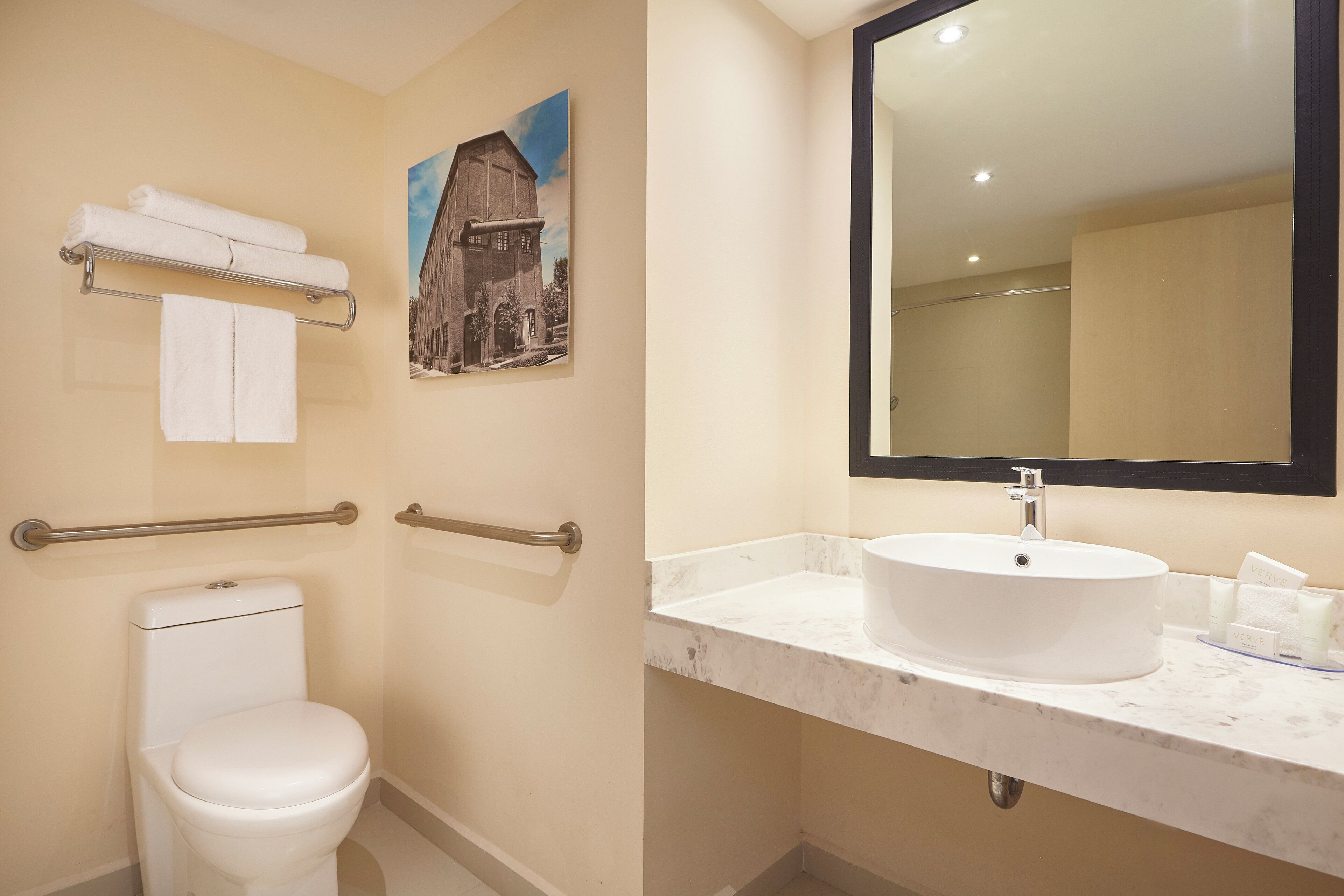 A bathroom with a toilet, a sink, a mirror, and a towel rack.