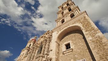 Un edificio histórico con detalles arquitectónicos intrincados, una imponente torre de campanas y una entrada arqueada grande.