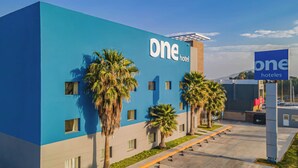 Un moderno edificio de hotel con fachada azul, palmeras y un letrero que dice 'one hotel'.