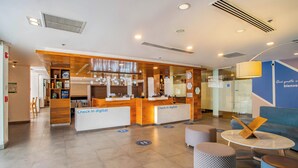 Un moderno vestíbulo de hotel con mostradores de recepción, zonas de estar y un escritorio de atención al cliente.