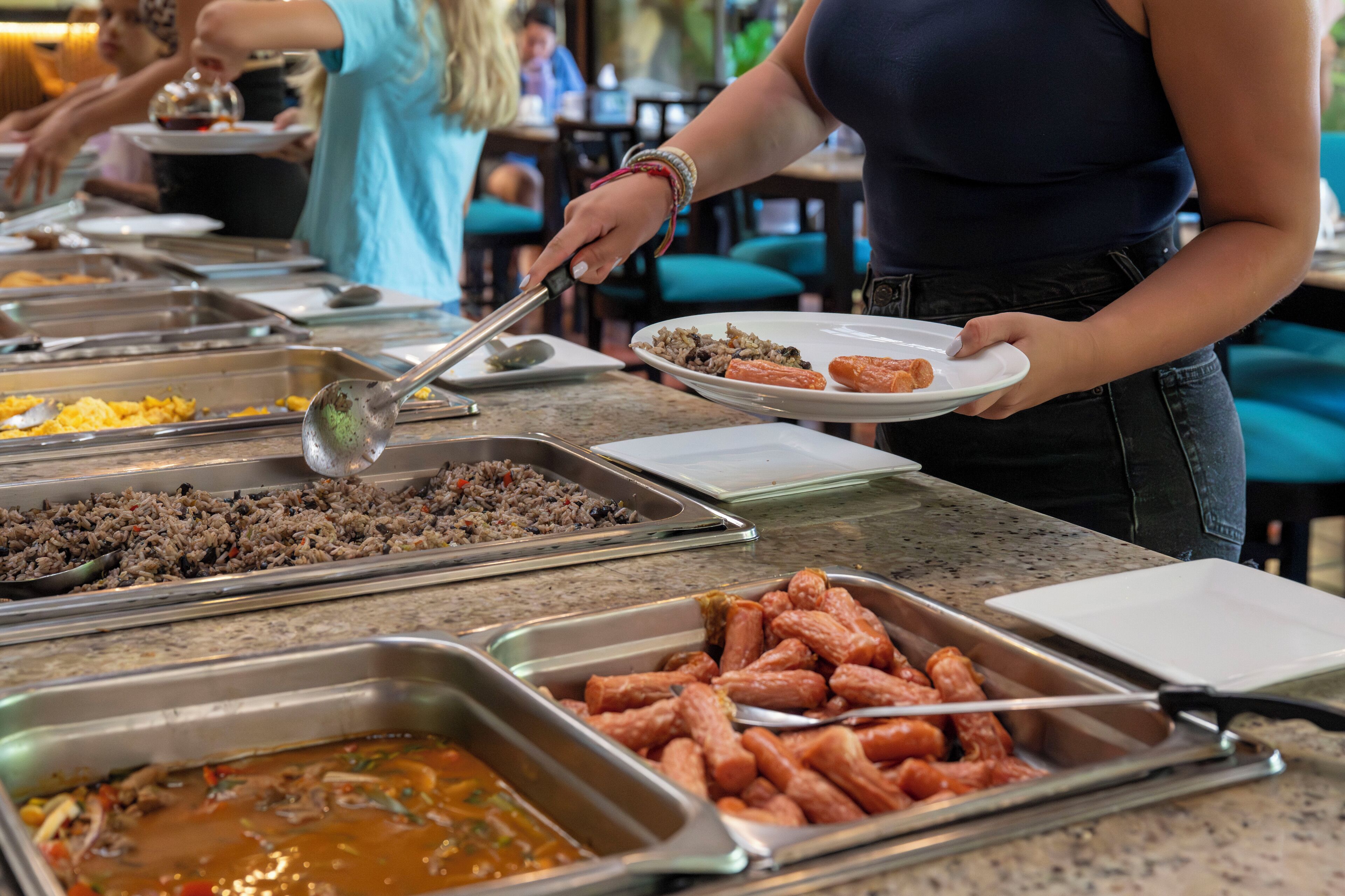 A buffet with various food options including hot dogs, rice, and a soup dish.
