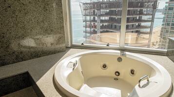 Un bagno con una vasca, una finestra che si affaccia su un cantiere edile e una spiaggia.
