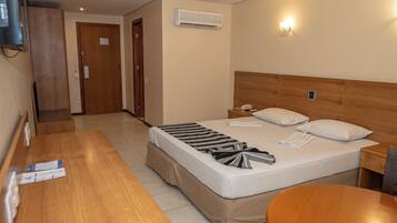 A hotel room with a bed, bedside table, a desk, and a chair.