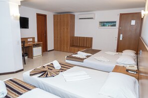 A hotel room with two single beds, a desk, a wardrobe, a television, and an air conditioning unit. - Costa Do Mar Hotel (Fortaleza)