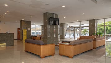Um hall de entrada com balcão de recepção, área de estar e amplas janelas.