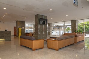 Un hall d’entrée avec un comptoir de réception, un espace salon et de grandes fenêtres.