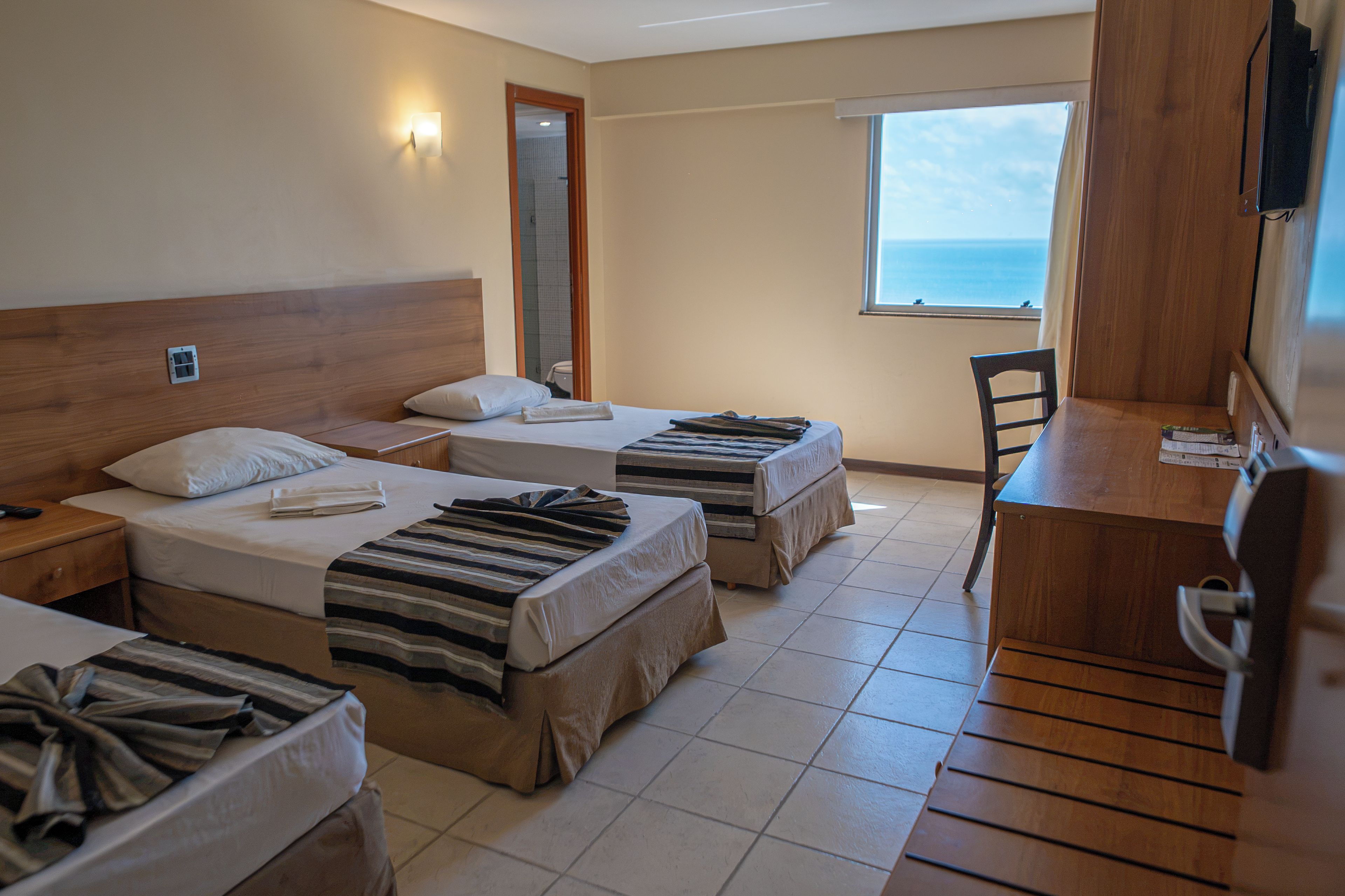 Habitación de hotel con dos camas individuales, un escritorio y una silla.