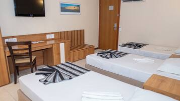 A hotel room with a desk, two beds, a chair, and a television.