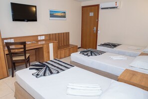 Een hotelkamer met een bureau, twee bedden, een stoel en een televisie.