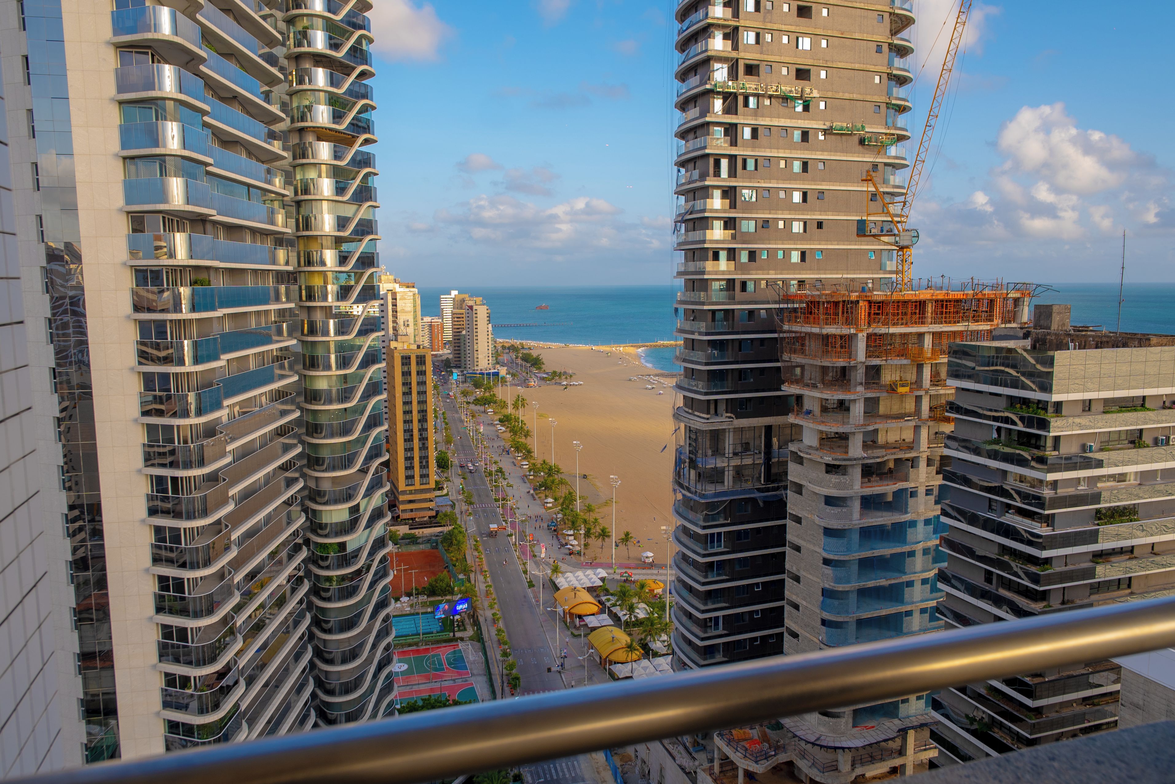 A high-rise building with a curved facade overlooking a beach.