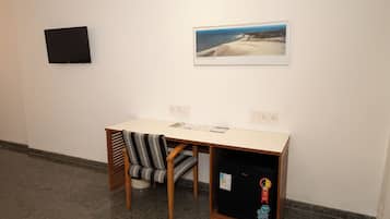 A room with a desk, chair, and a small refrigerator.