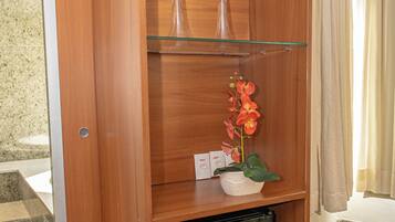 A wooden cabinet with glass shelves, a small refrigerator, and a potted plant.