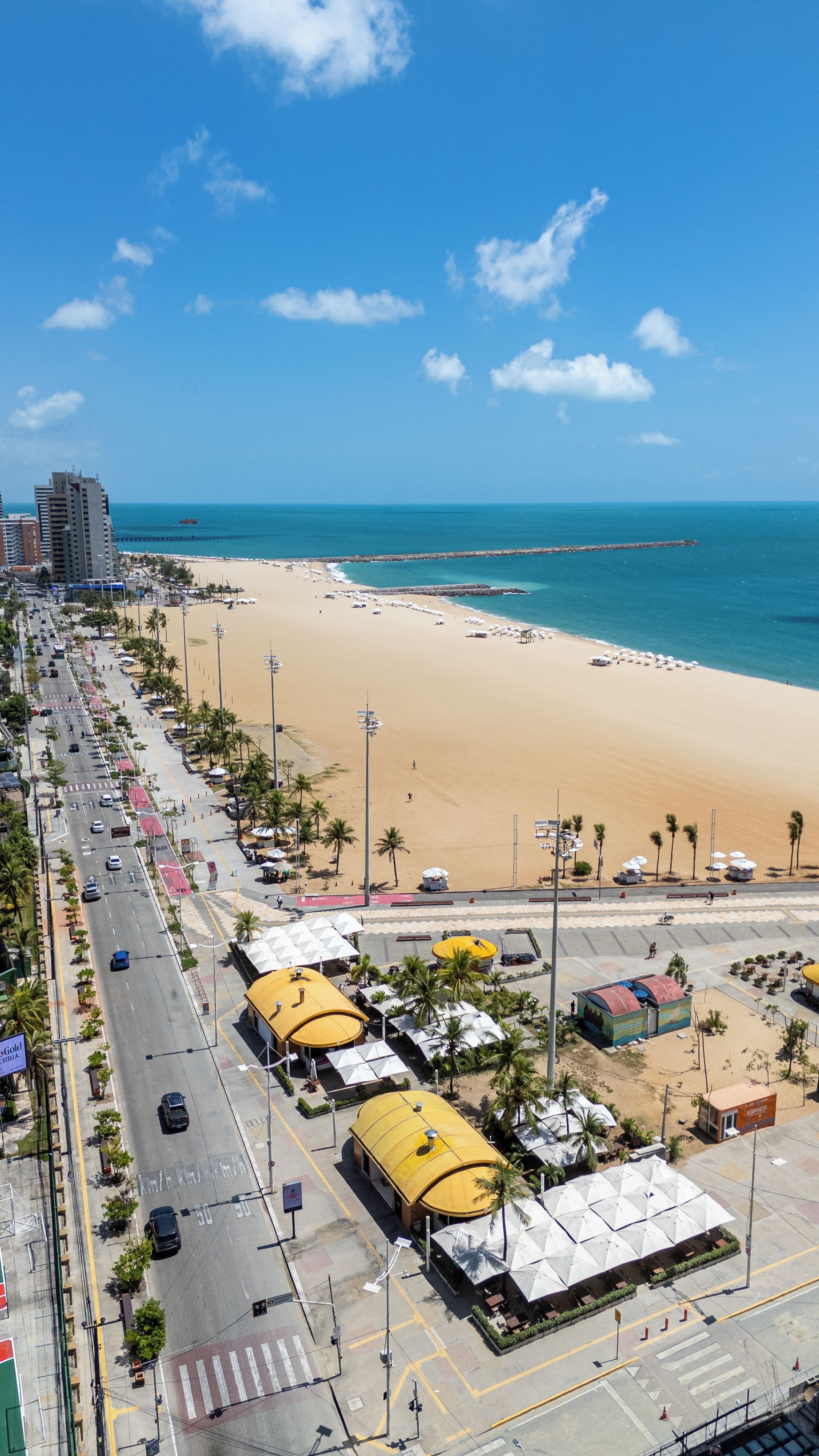 Paesaggio costiero con spiaggia, edifici e strada.