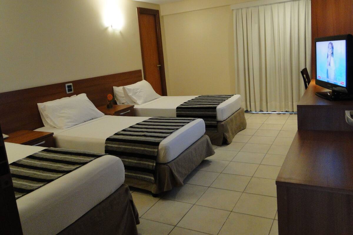 A hotel room with two beds, a TV, and a desk.