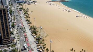 An aerial view of a beachside area with a road, buildings, and a beach.
