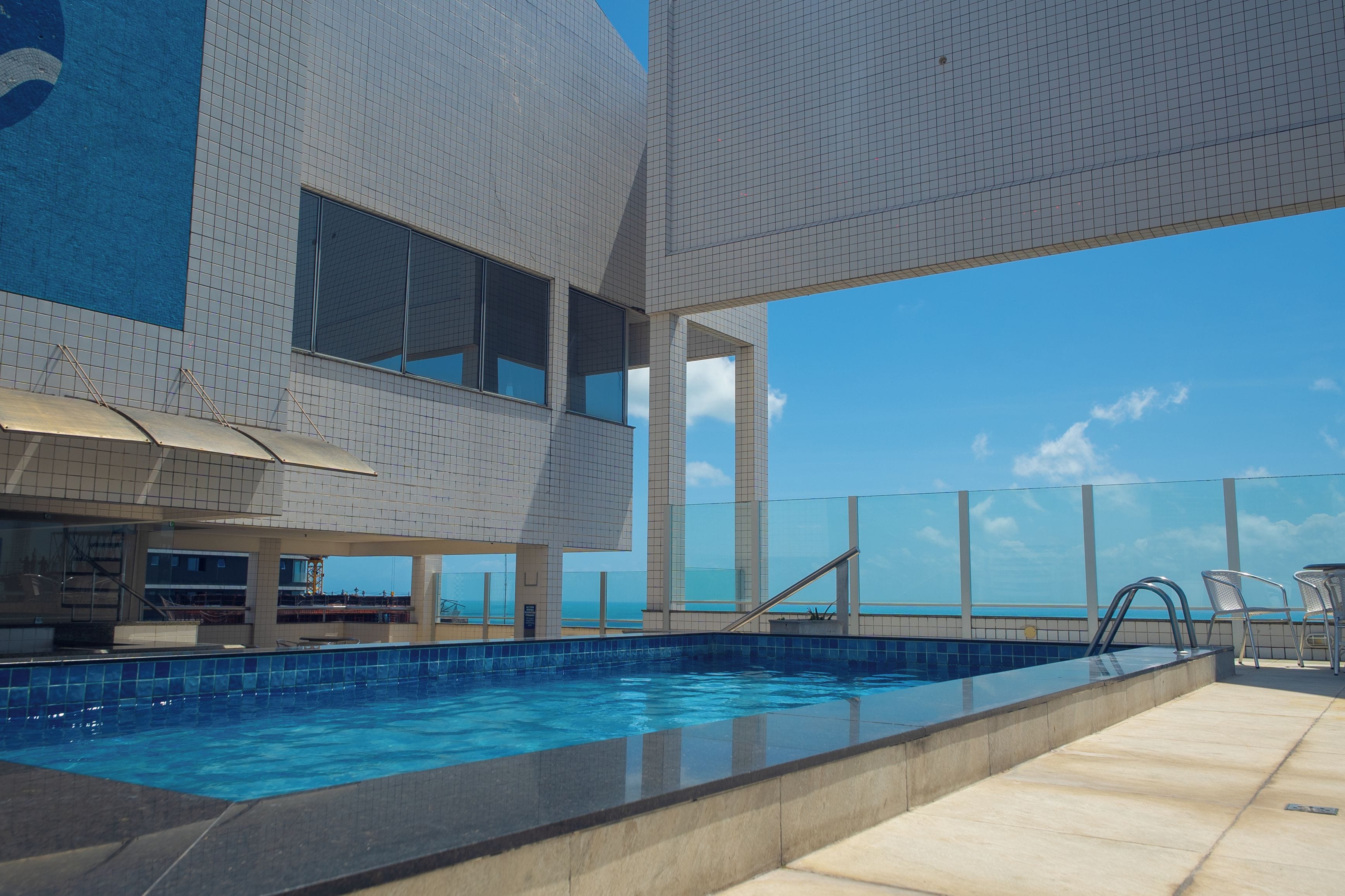 Un edificio moderno con piscina, ventanas amplias y vista al océano.