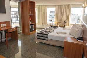 Une chambre d’hôtel comprenant un lit, un bureau, une chaise, une petite table et une bibliothèque.