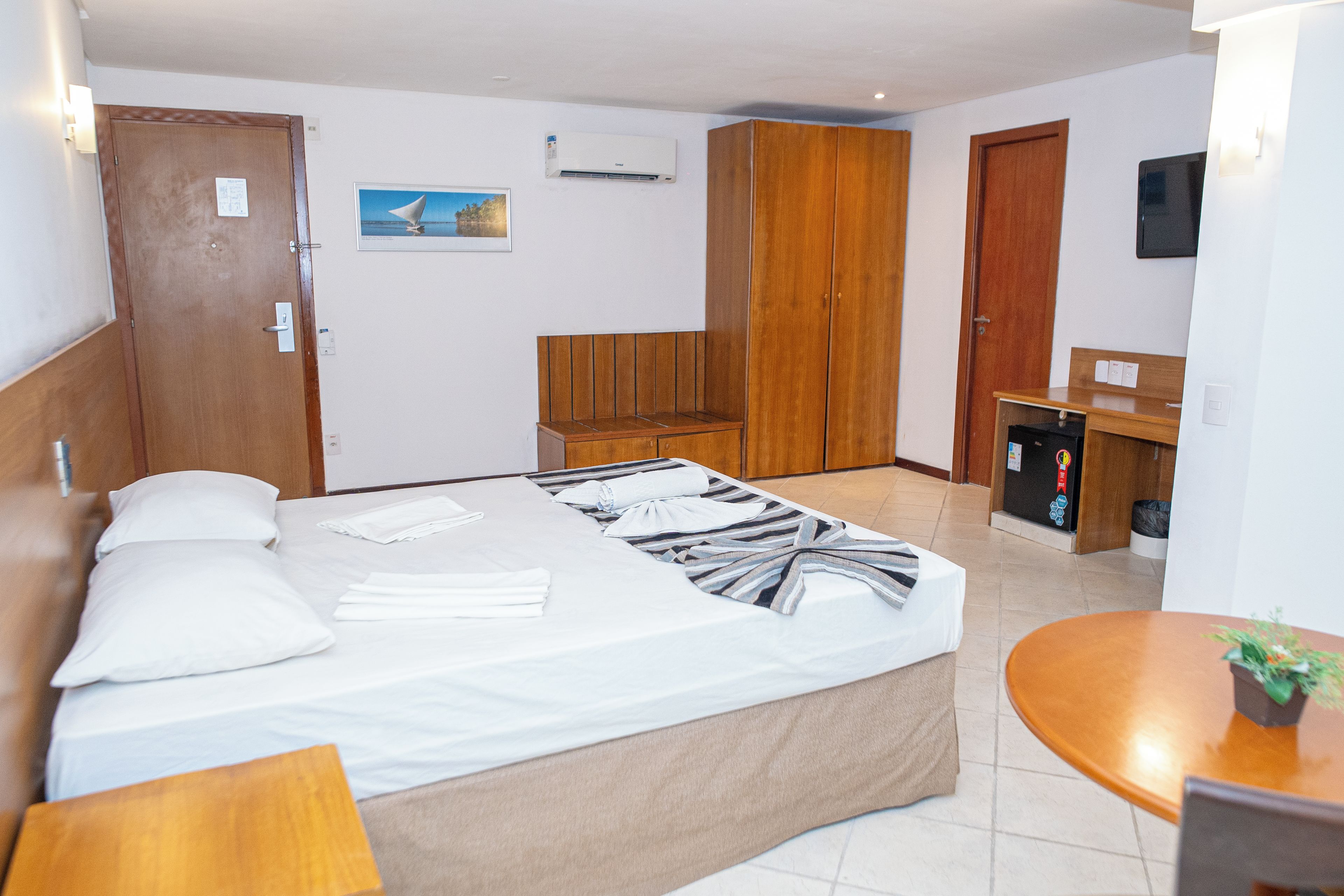 A hotel room with a bed, a desk, a wardrobe, and a small kitchenette.