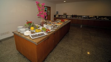 A buffet setup with various food items and a vase of flowers.