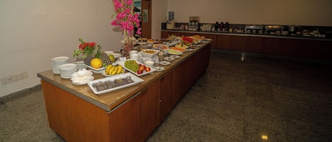 Mesa de buffet con diversos alimentos y un jarrón de flores.