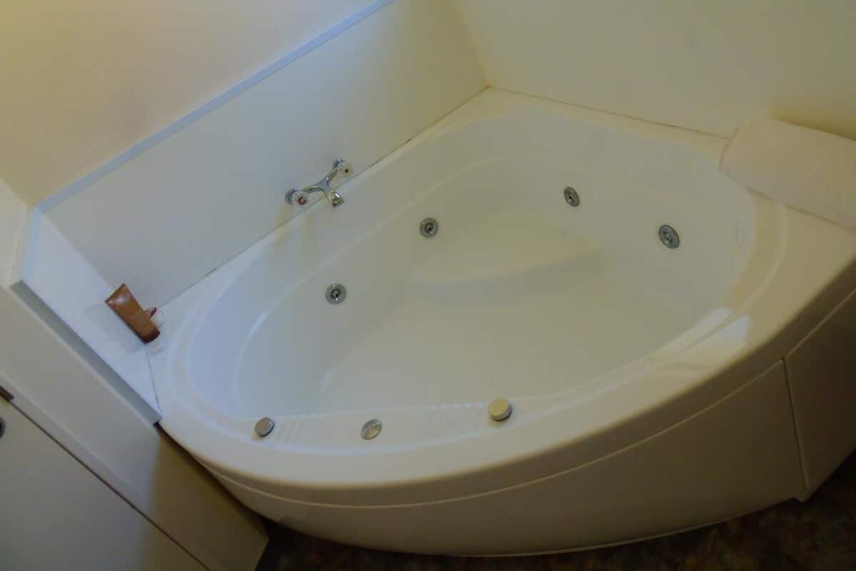 Eine Eckbadewanne mit Wasserhahn und Armatur.