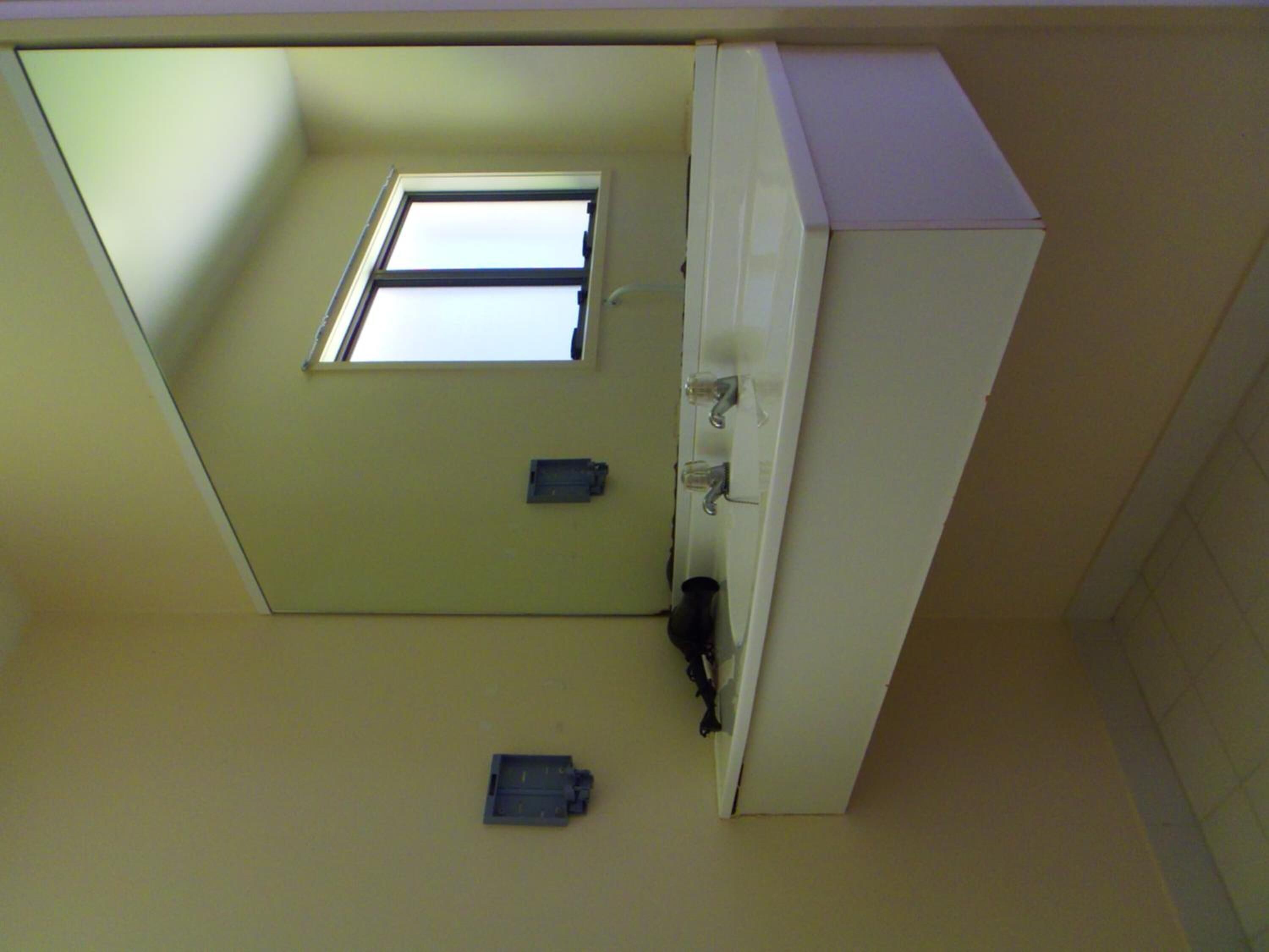 A room with a small window, a door, and a light switch on the wall.