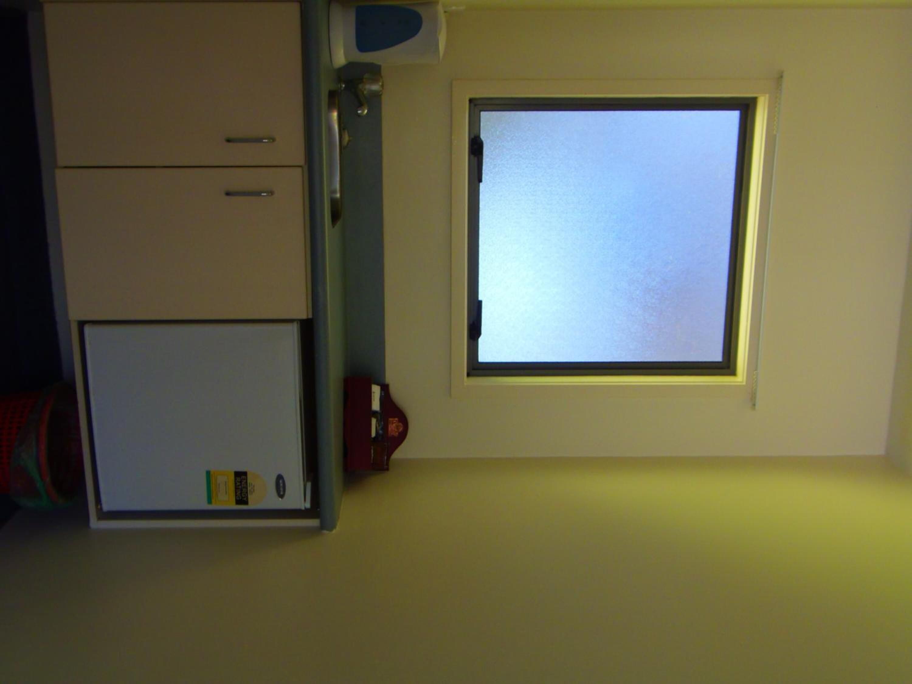 A room with a window, a door, and a small cabinet.