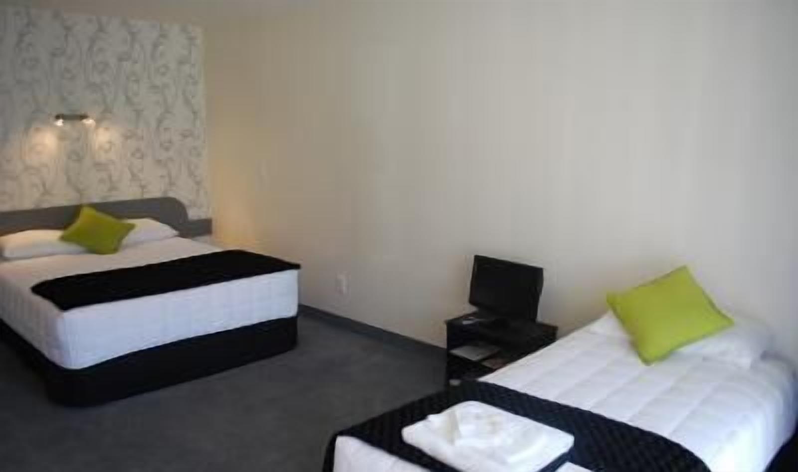 A hotel room with two beds, a desk, and a chair.