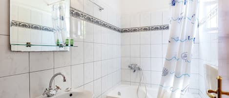 Une salle de bain équipée d’un lavabo, d’un miroir, d’une douche et de toilettes.