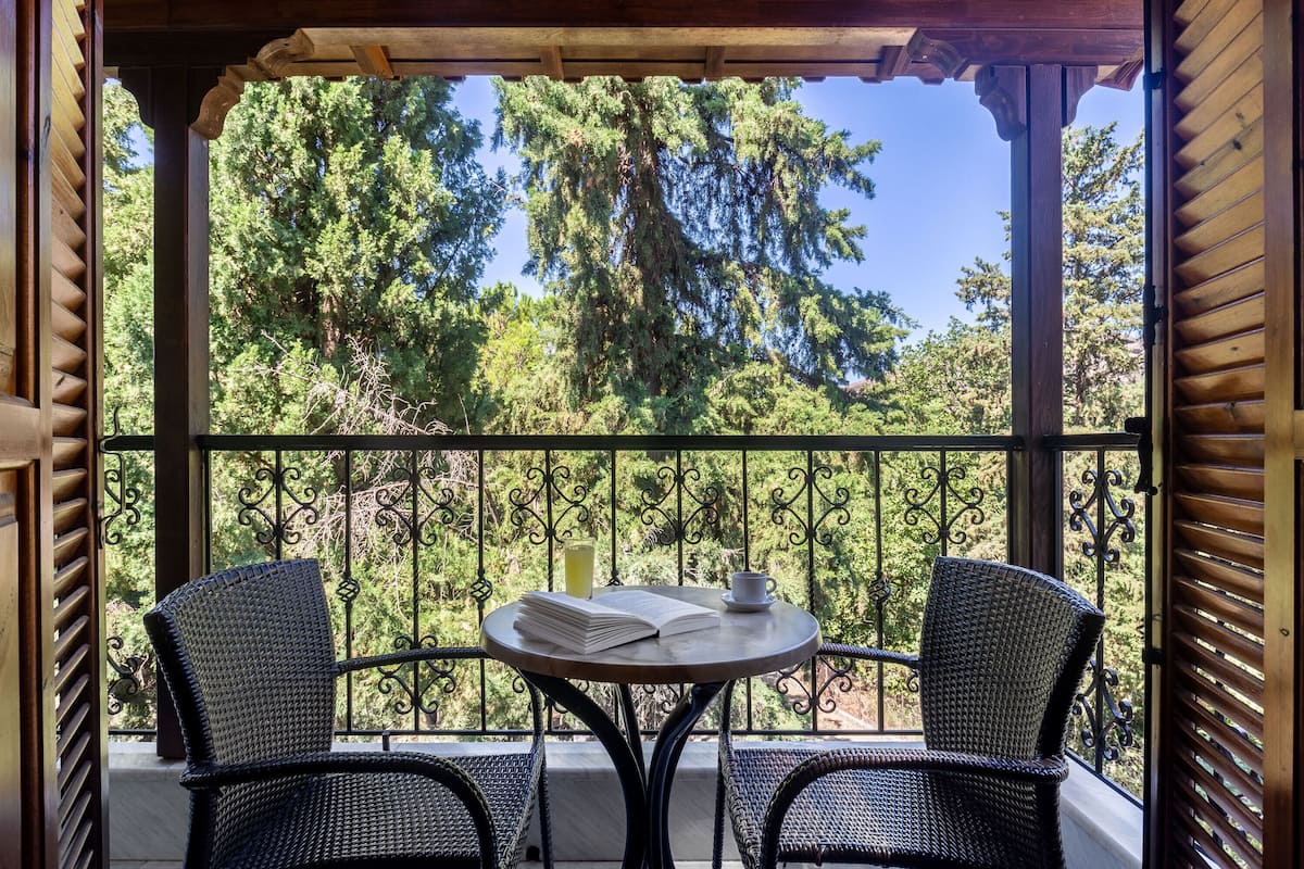 A balcony with two wicker chairs, a small round table, and a book.