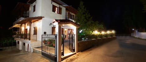 A two-story house with a balcony, a gated entrance, and a paved driveway.