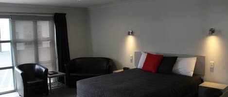 A modern hotel room with a large bed, a desk, and a chair.