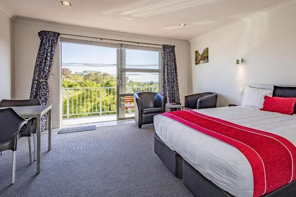 Habitación de hotel con una cama grande, un escritorio y un balcón con vistas.