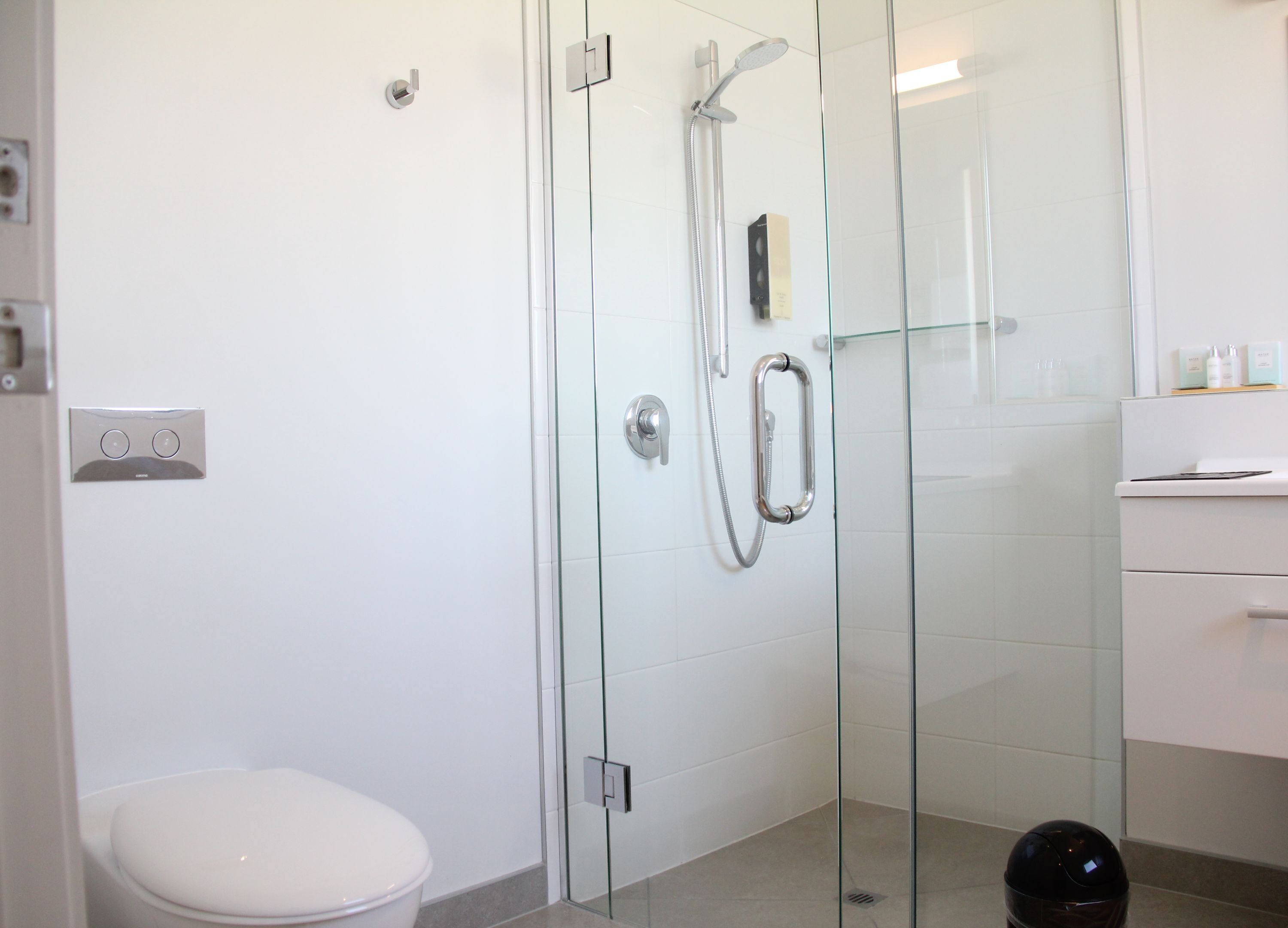 A modern bathroom with a glass-enclosed shower, a toilet, and a white sink.