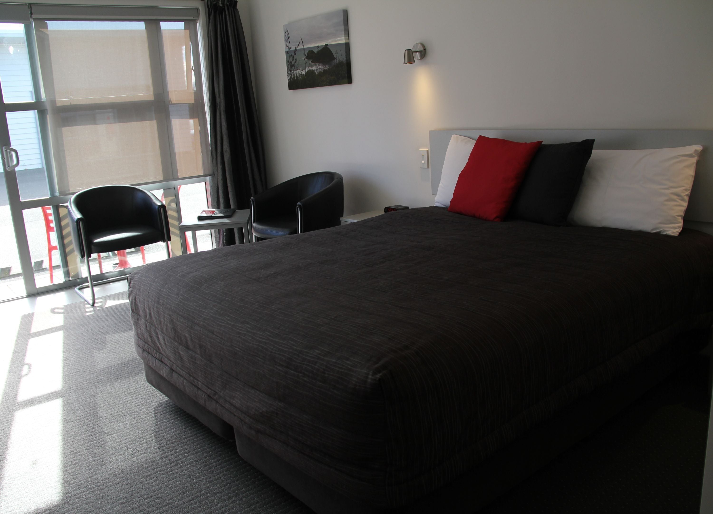 Een hotelkamer met een groot bed, een bureau, een stoel en uitzicht door een glazen deur.