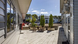 A covered outdoor area with tiled flooring, potted plants, and outdoor furniture. - ASURE Pukekura Motor Lodge (New Plymouth)