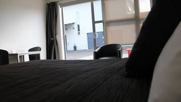 A hotel room with a bed, a desk, a chair, and a view of the outside.