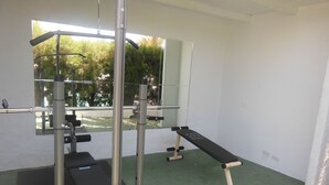 A gym with a bench, weight rack, and mirrors.