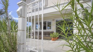 A building entrance with a white gate, potted plants, and a bench. - Hotel Hola (Florianópolis)